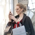 Woman holding smartphone with shopping bags